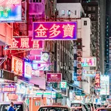A city street at night under stacked pink and magenta neon signs