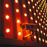 A surveillance camera in front of a wall of glowing red and orange lights