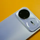 A smartphone's raised camera module in close-up against a bright yellow backdrop