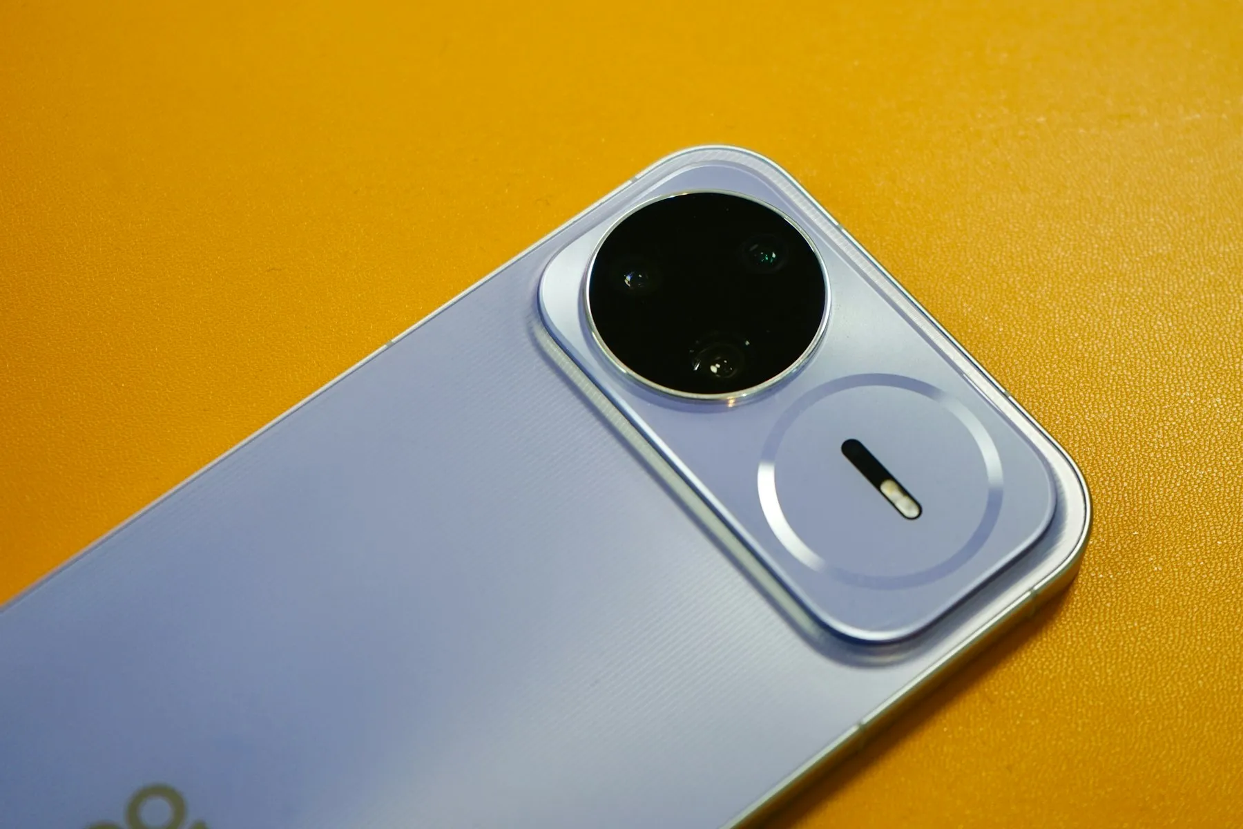 A smartphone's raised camera module in close-up against a bright yellow backdrop