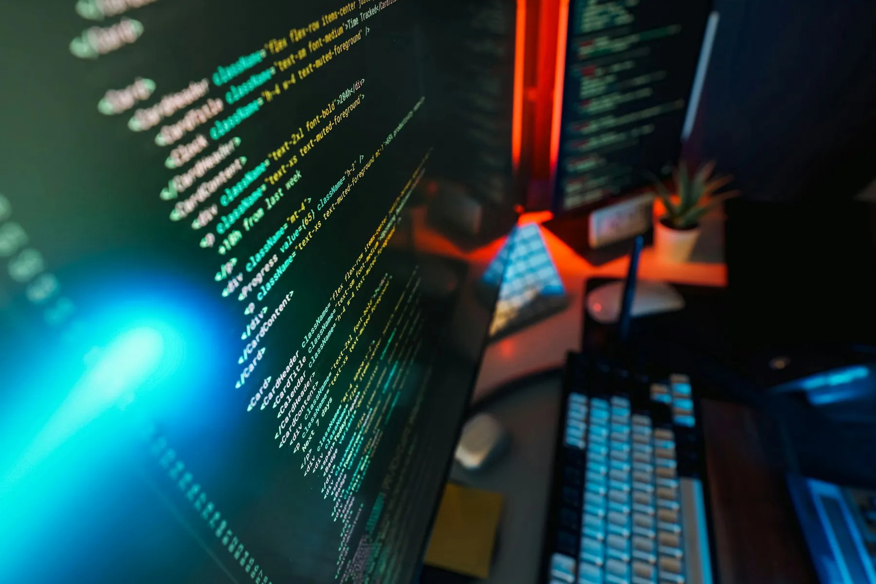 Code filling two monitors lit by cyan and orange light
