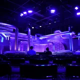 A television studio lit in deep purple with large screens behind the stage