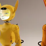 Two amber-coloured humanoid robots with glowing animated faces